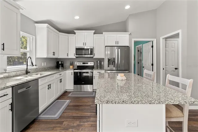 a kitchen with granite countertop white cabinets and a window
