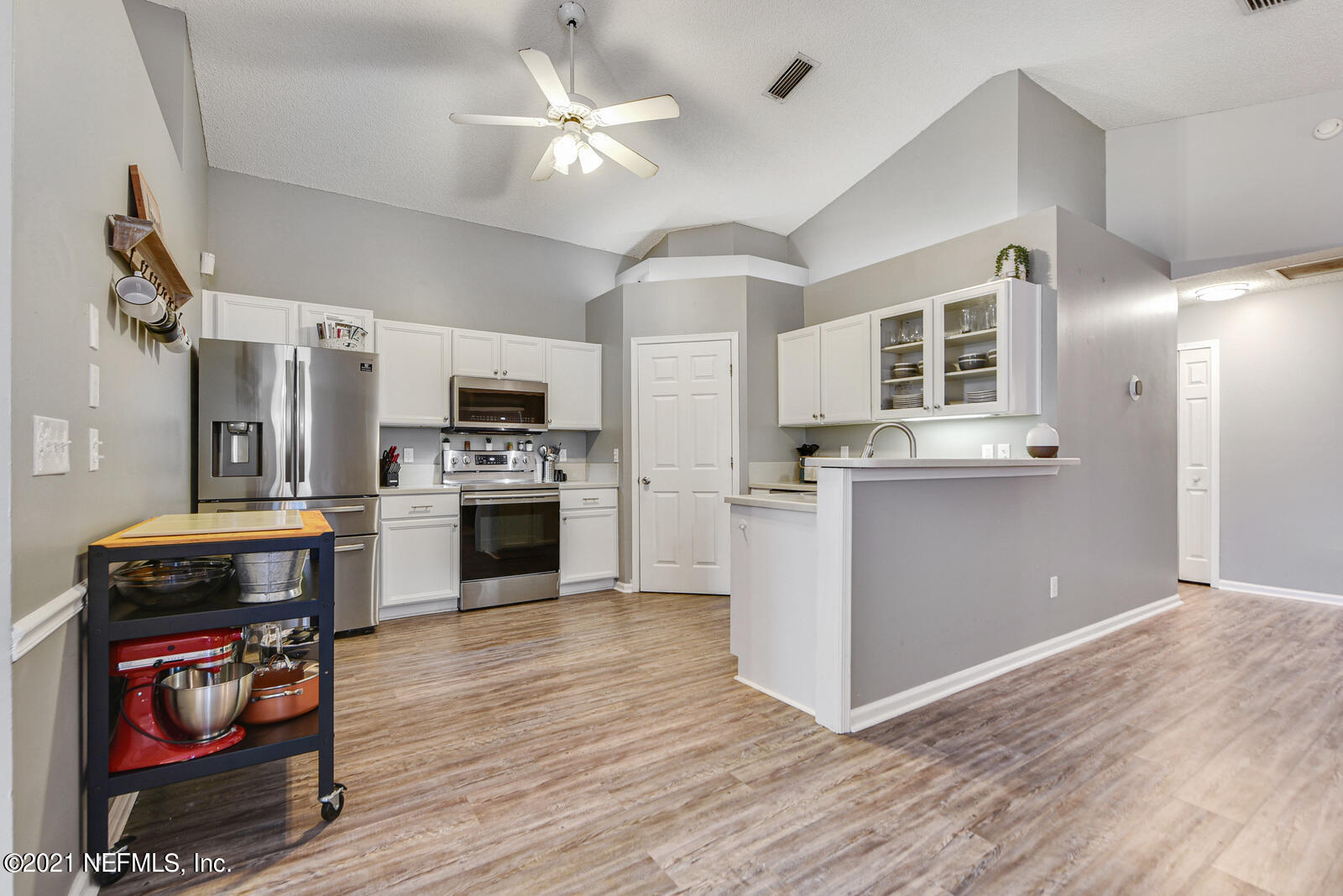 5434 Fort Caroline Road Jacksonville, FL 32277 - Photo 26 of 26 a kitchen with a refrigerator a stove top oven a chimney cabinets and wooden floor