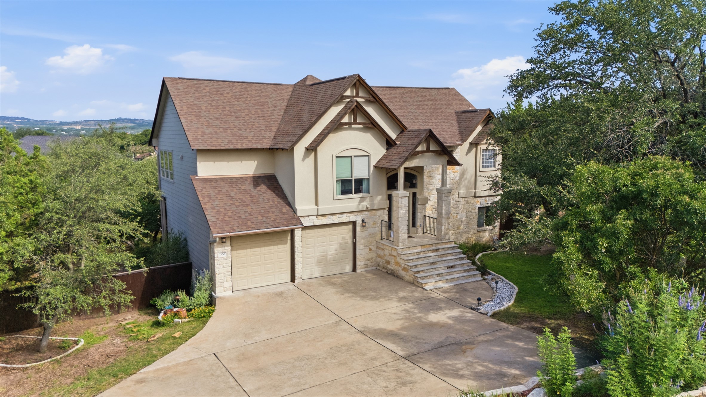 700 Augusta Circle Point Venture, TX 78645 - Photo 2 of 35 A spacious home with a two-car garage and a grand stone entryway, set amidst lush green landscaping.