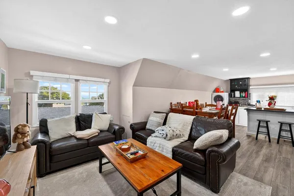 a kitchen with stainless steel appliances granite countertop a stove top oven a sink a dining table and chairs with wooden floor