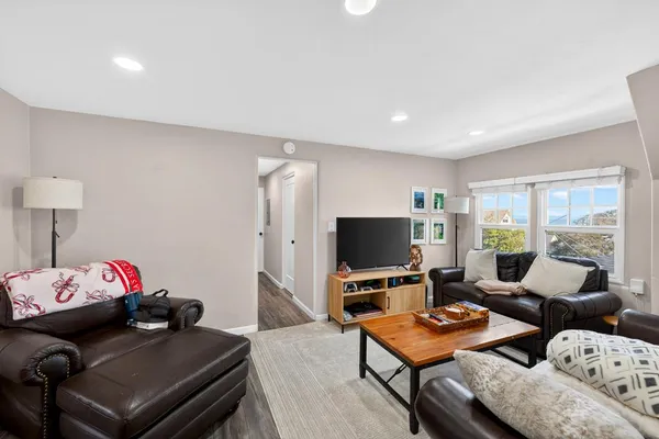 a living room with furniture kitchen view and a large window