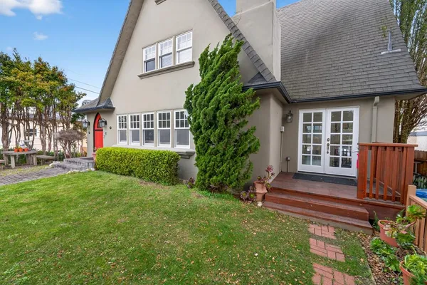 a view of a house with wooden fence and potted plants
