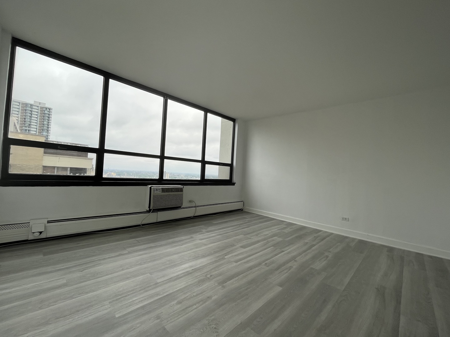 6171 North Sheridan Road, Unit 2502 Chicago, IL 60660 - Photo 13 of 28 an empty room with wooden floor and windows