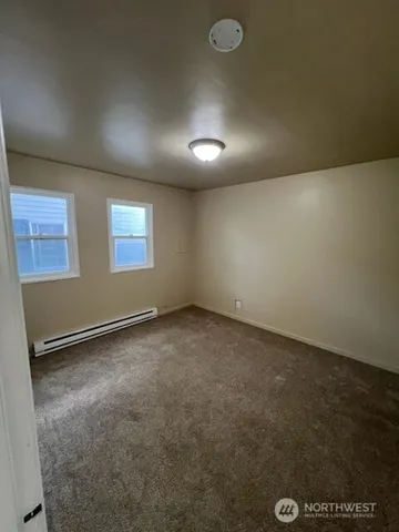 a backyard of a house with plants and large tree
