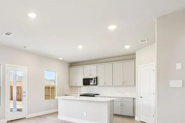 a kitchen with granite countertop white cabinets and black stainless steel appliances