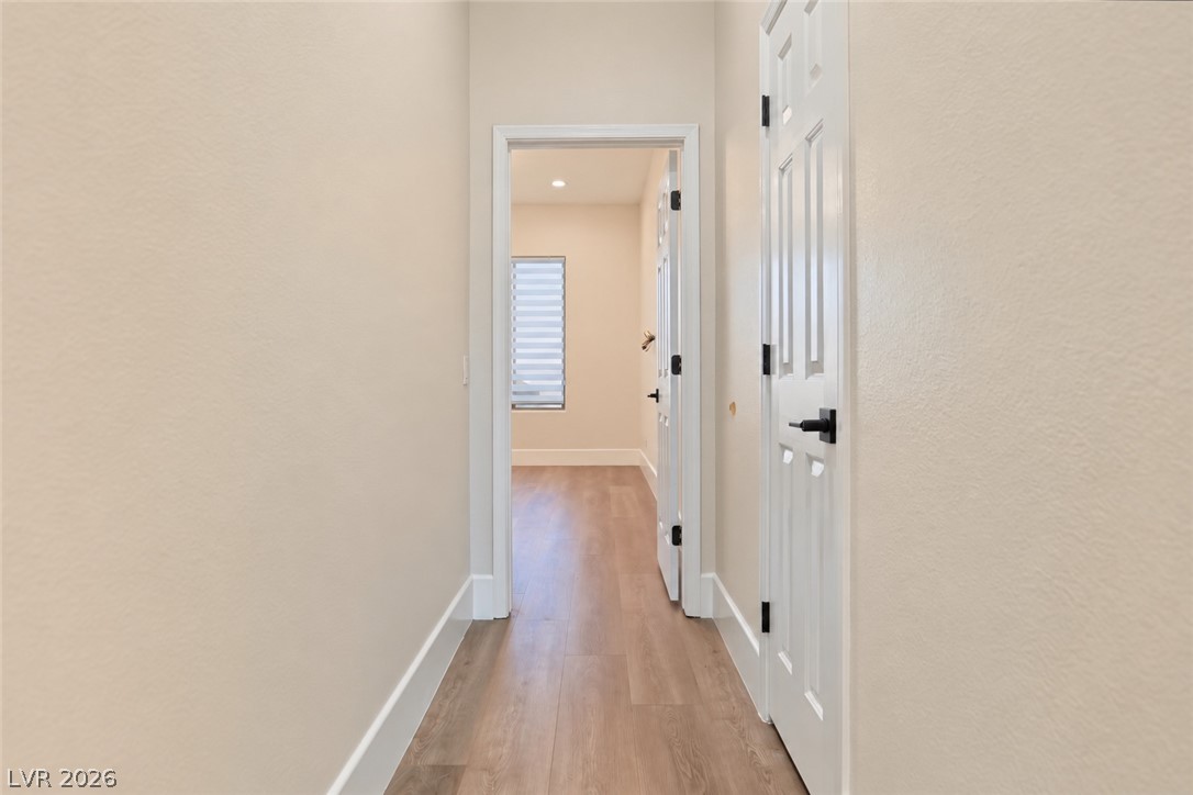 6 Mohansic Road Henderson, NV 89052 - Photo 16 of 38 Smooth plaster walls and warm wood-look floors frame a bright, straightforward hallway transition.