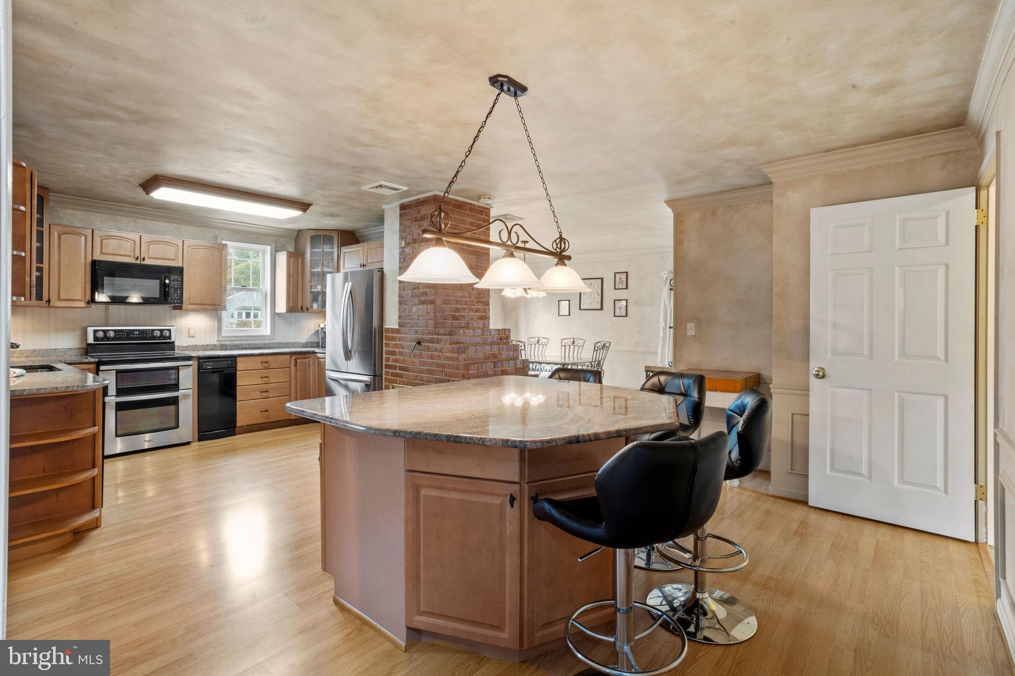 74 Gaping Rock Road Levittown, PA 19057 - Photo 10 of 31 a kitchen with stainless steel appliances granite countertop a kitchen island hardwood floor sink stove dining table and chairs