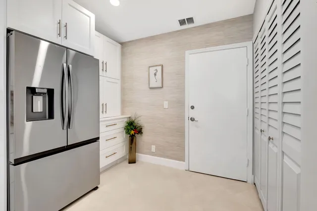 a view of a refrigerator in kitchen and an empty room
