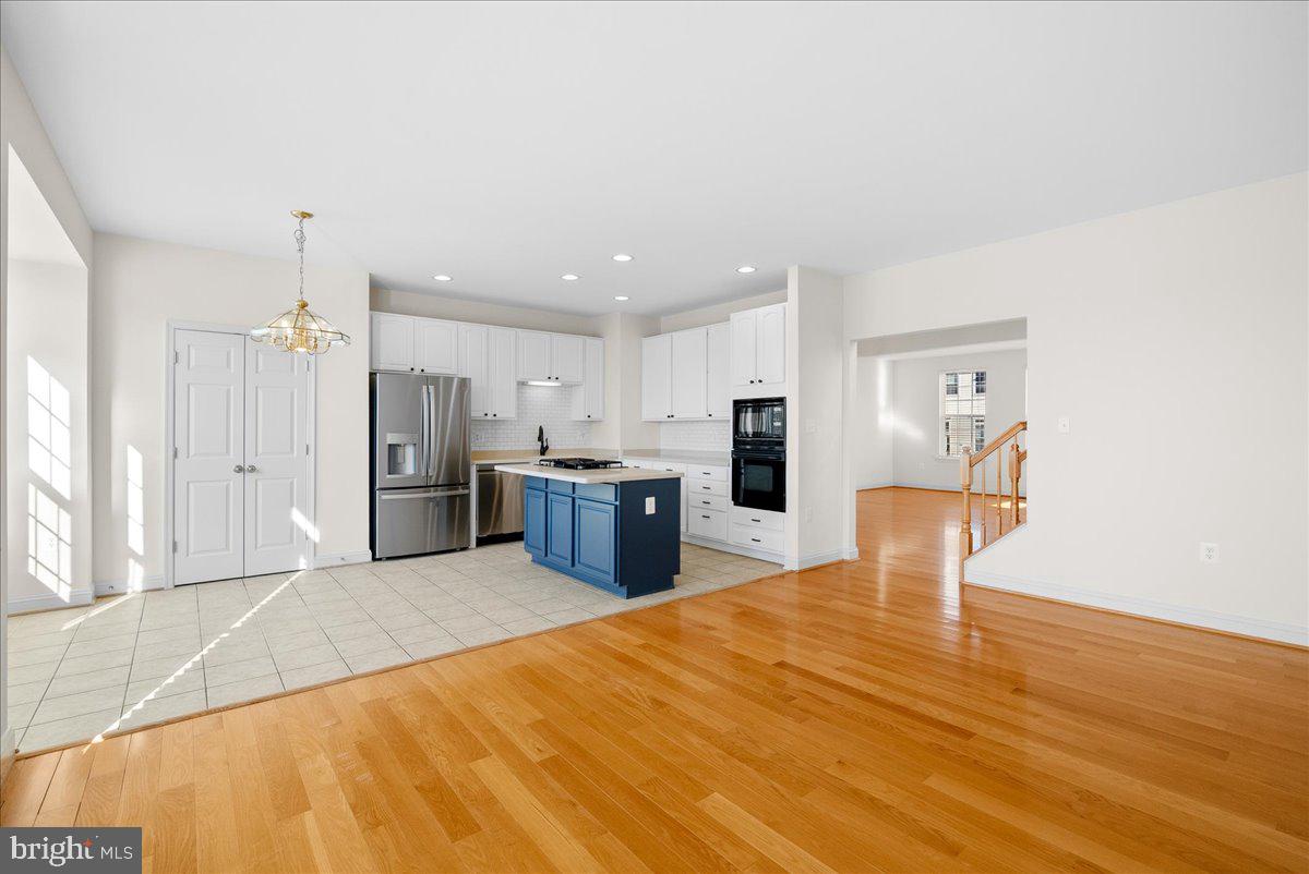 927 Buttonwood Terrace Northeast Leesburg, VA 20176 - Photo 13 of 44 a large room with stainless steel appliances kitchen island a stove a refrigerator a dining table and chairs with wooden floor