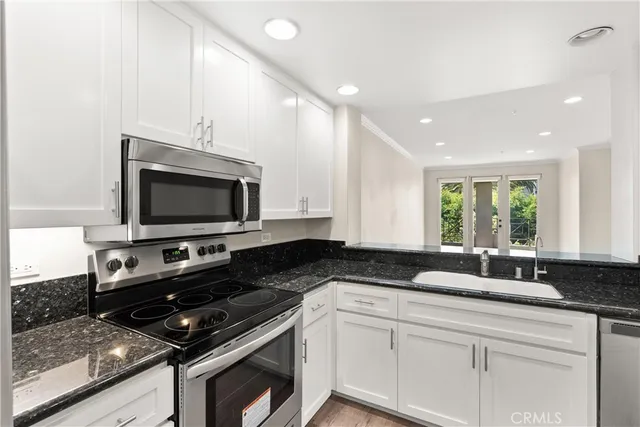 a kitchen with stainless steel appliances a stove a microwave a sink and white cabinets