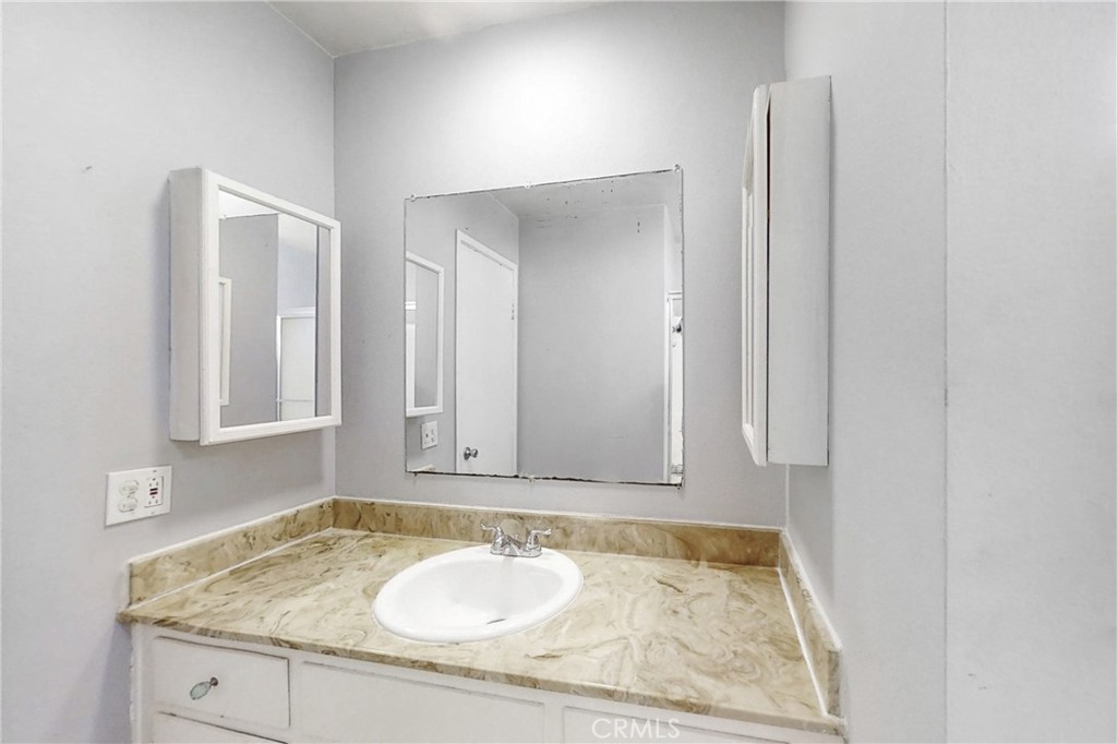545 Chestnut Avenue, Unit 406 Long Beach, CA 90802 - Photo 13 of 16 a bathroom with a granite countertop sink and a mirror