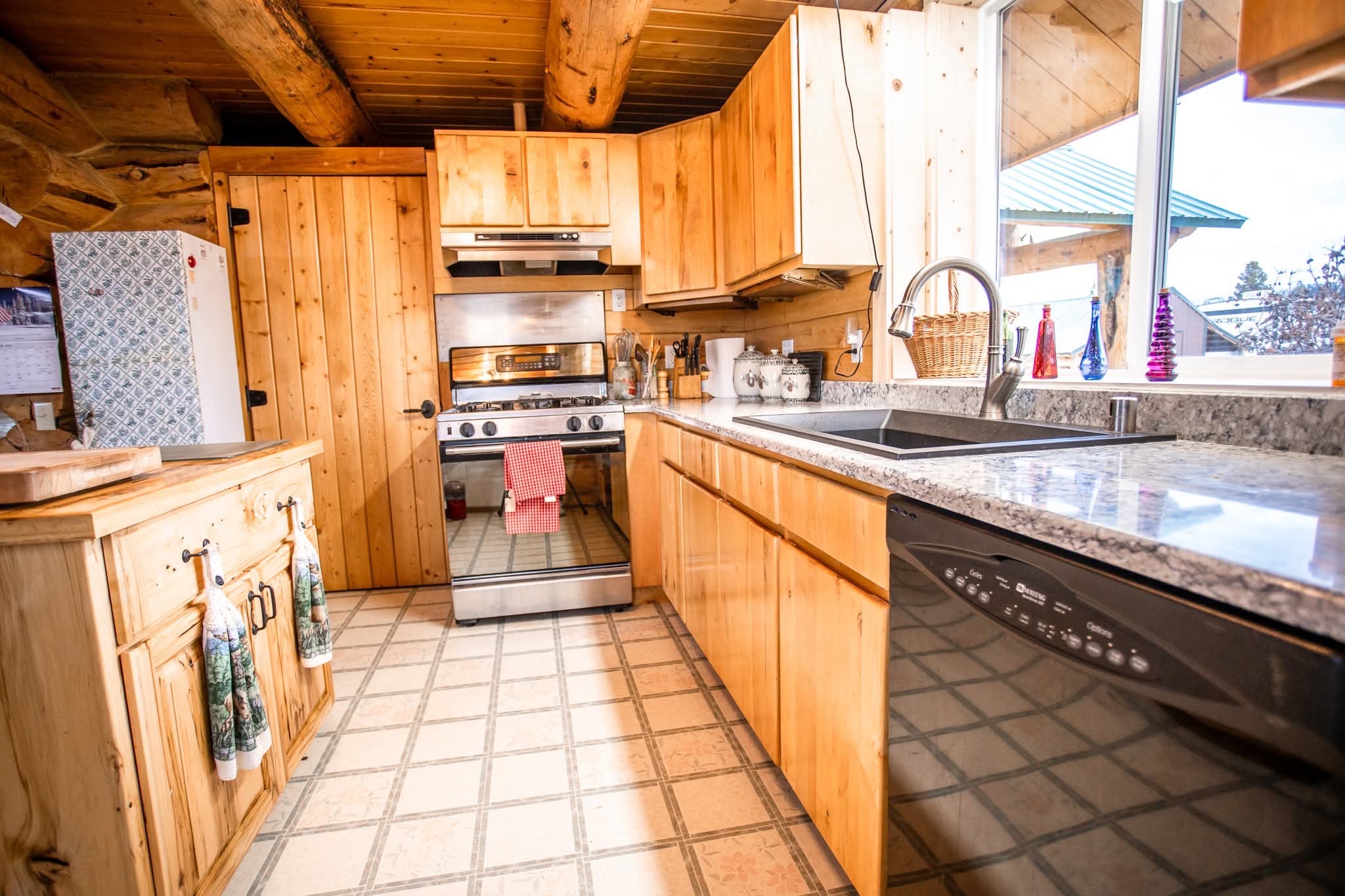 3358 Strandskov Road Lincoln, MT 59639 - Photo 8 of 80 Kitchen featuring dishwasher, wooden ceiling, sink, stainless steel gas range, and beamed ceiling