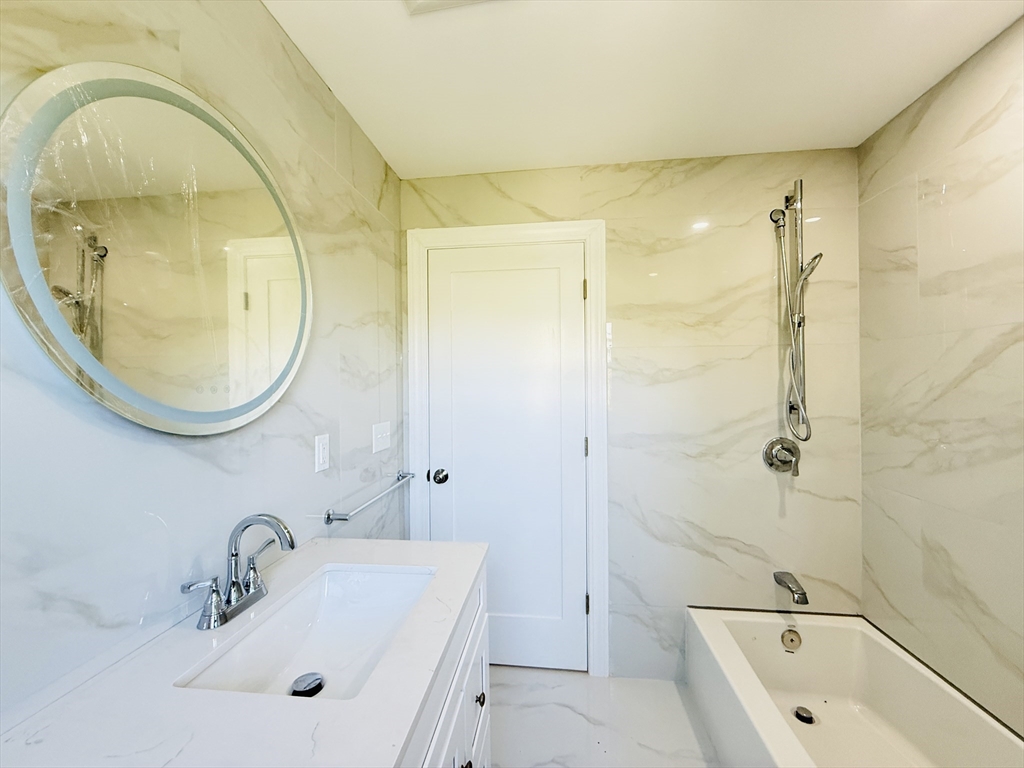 4 Baldwin Street, Unit 4 Newton, MA 02458 - Photo 21 of 30 a bathroom with a sink a mirror a bathtub and a shower