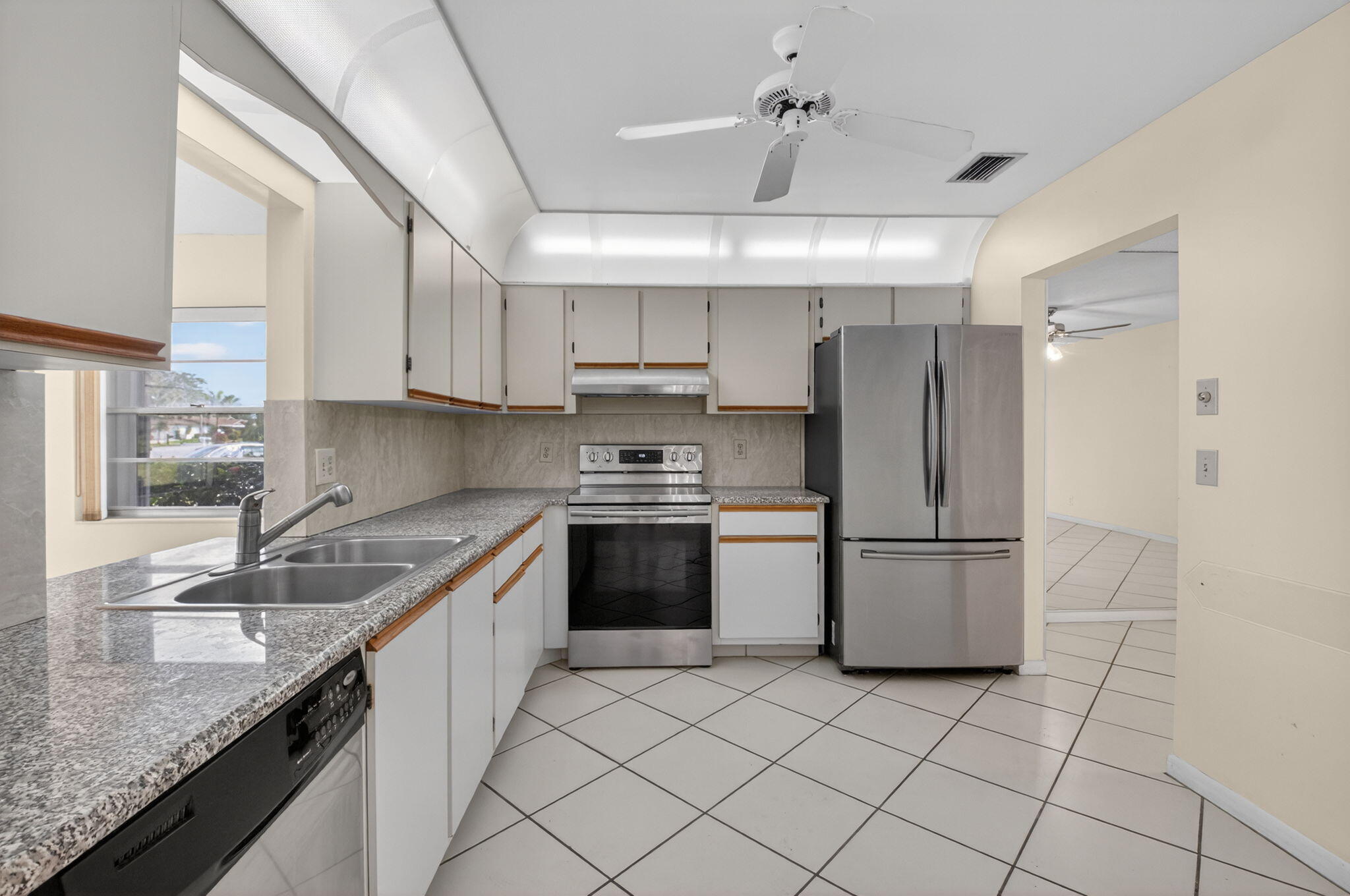 6321 Lasalle Road Delray Beach, FL 33484 - Photo 9 of 38 a kitchen with a sink a refrigerator and cabinets