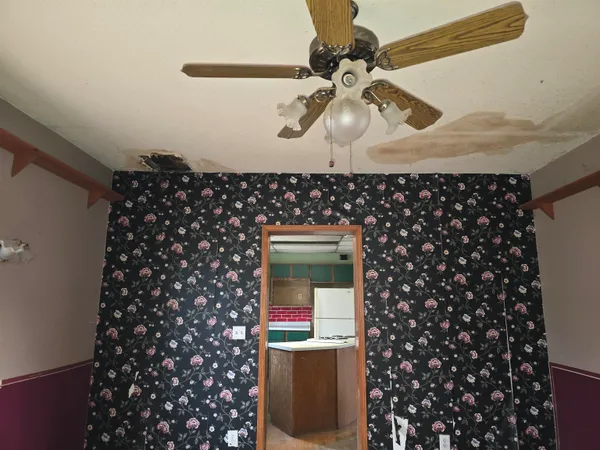 a room with a chandelier fan and wooden floor