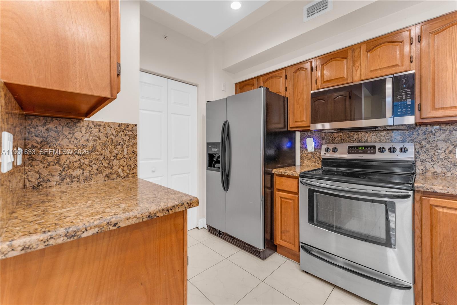 2400 East Preserve Way, Unit 101 Miramar, FL 33025 - Photo 11 of 41 a kitchen with stainless steel appliances granite countertop a stove a microwave and a refrigerator