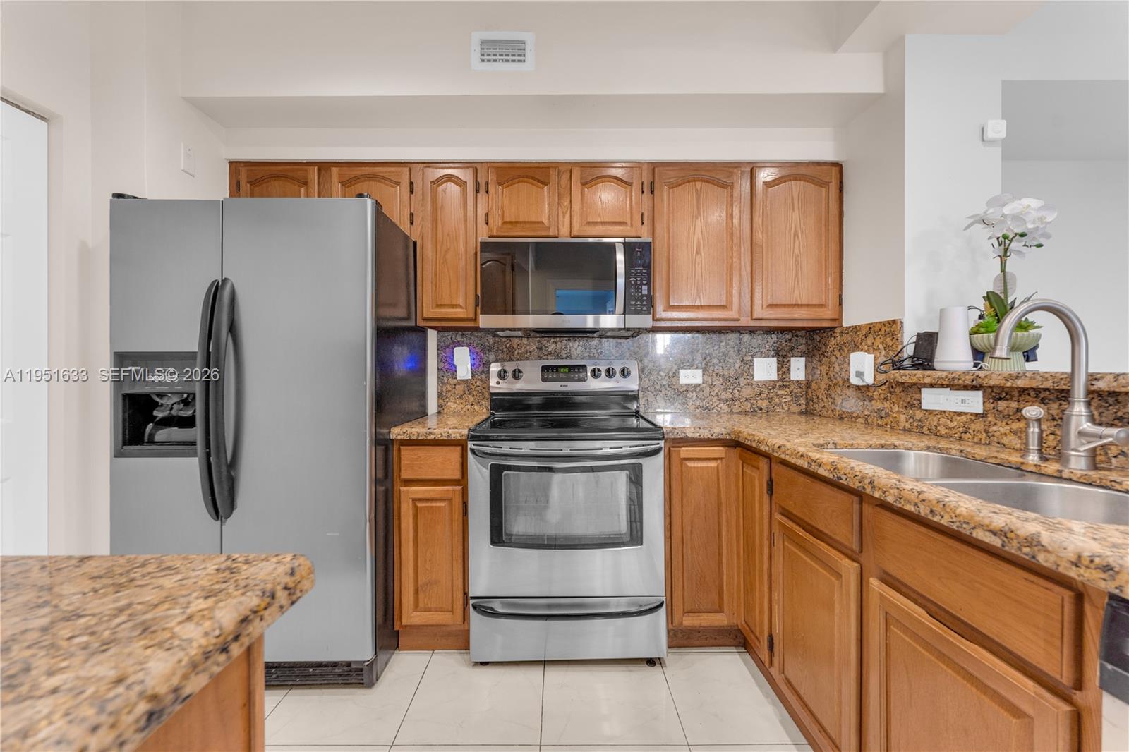 2400 East Preserve Way, Unit 101 Miramar, FL 33025 - Photo 12 of 41 a kitchen with stainless steel appliances granite countertop a refrigerator stove and sink