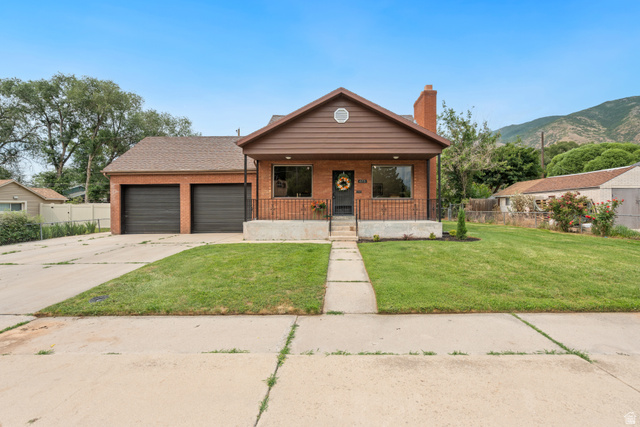 673 East 700 South Springville, UT 84663 - Photo 1 of 43 Brick exterior residence featuring a two-car garage, front porch with wrought iron railing, and a manicured lawn