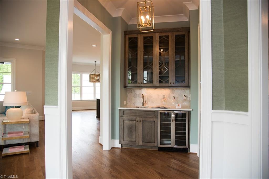 6900 Matzinger Court Oak Ridge, NC 27310 - Photo 4 of 30 Wet bar featuring silhouette beverage center, custom cabinetry and Champagne Bronze Contemporary Collection faucet.