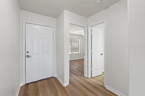 a view of an empty room with a window and wooden floor