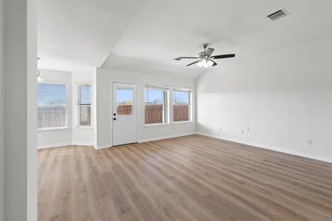 a view of an empty room with window and wooden floor