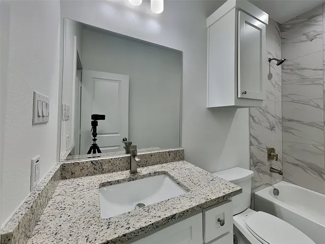 a bathroom with a granite countertop sink toilet and shower