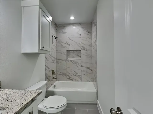 a bathroom with a granite countertop toilet a sink and bathtub