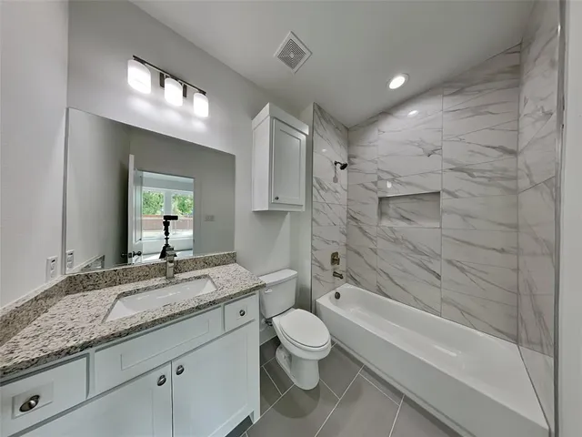 a bathroom with a granite countertop sink a toilet and bathtub