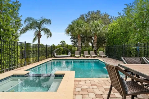 a view of a swimming pool with a lounge chair and palm trees
