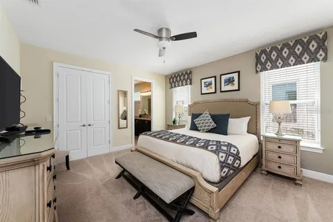 a spacious bedroom with a bed and a flat tv screen on the dresser