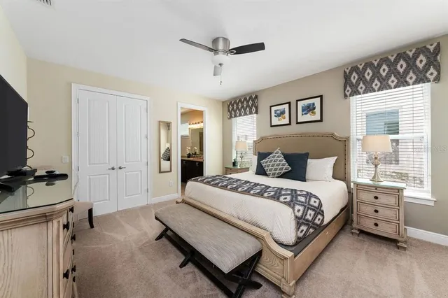 a spacious bedroom with a bed and a flat tv screen on the dresser