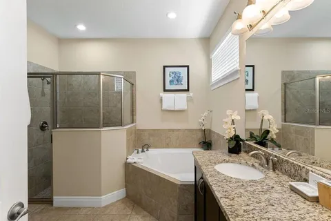 a bathroom with a granite countertop bathtub a sink and a mirror