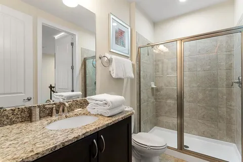 a bathroom with a granite countertop sink a toilet and shower