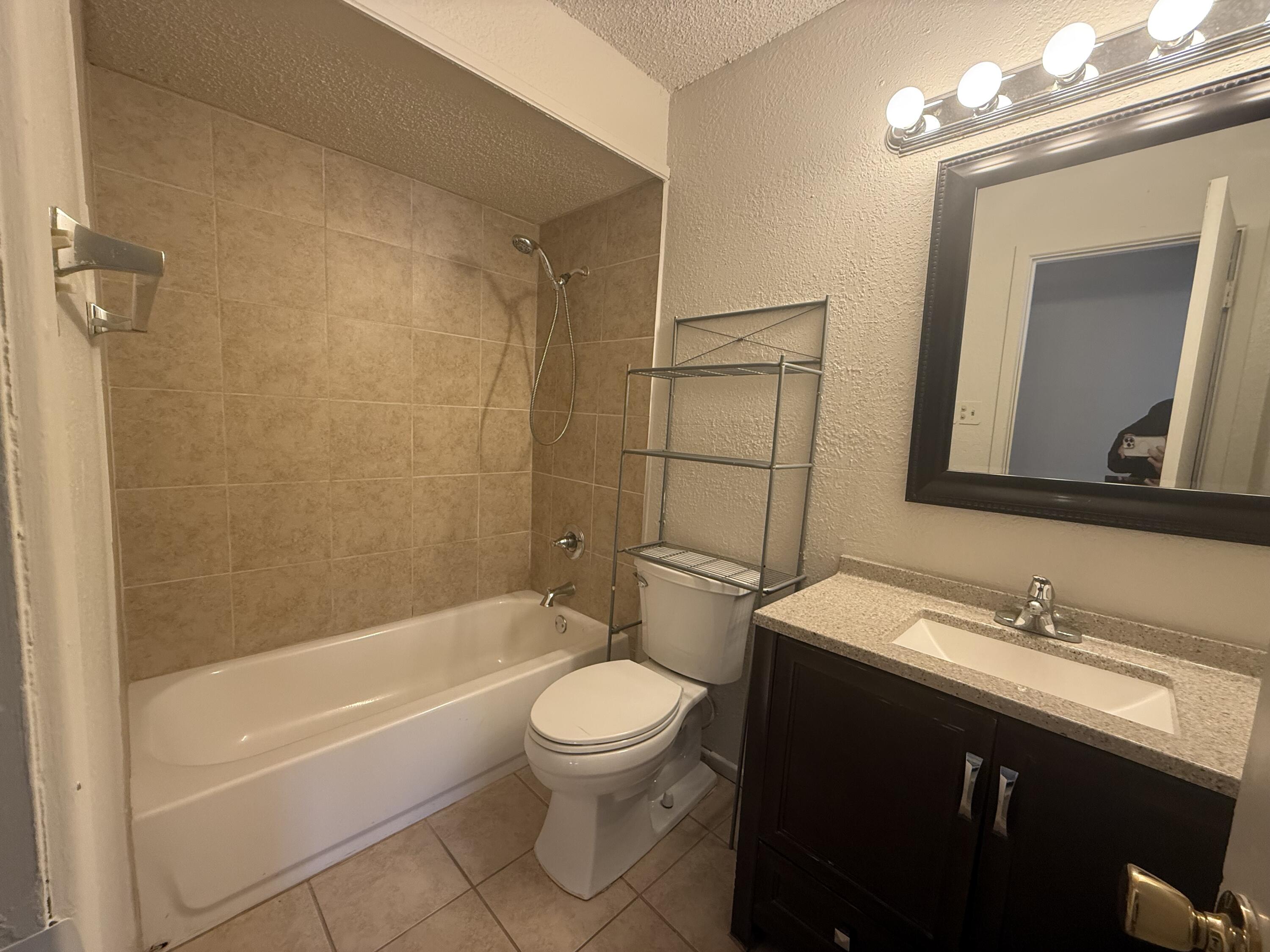 2317 15th Street Lubbock, TX 79401 - Photo 6 of 8 a bathroom with a toilet a sink a mirror and bathtub