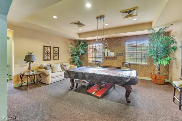 a living room with furniture pool table and a potted plant