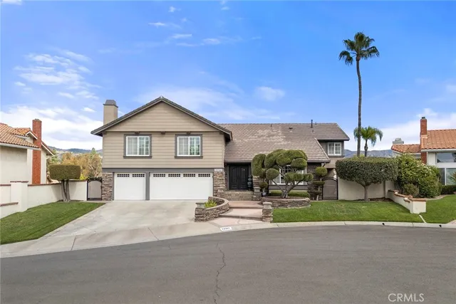 a front view of a house with a garden and mountain view