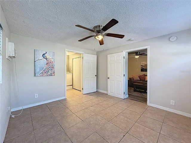 an empty room with wooden floor chandelier fan and windows
