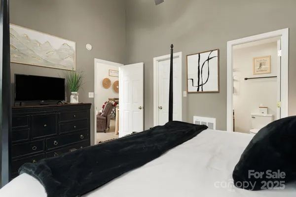 a bedroom with a bed and a flat tv screen on dresser