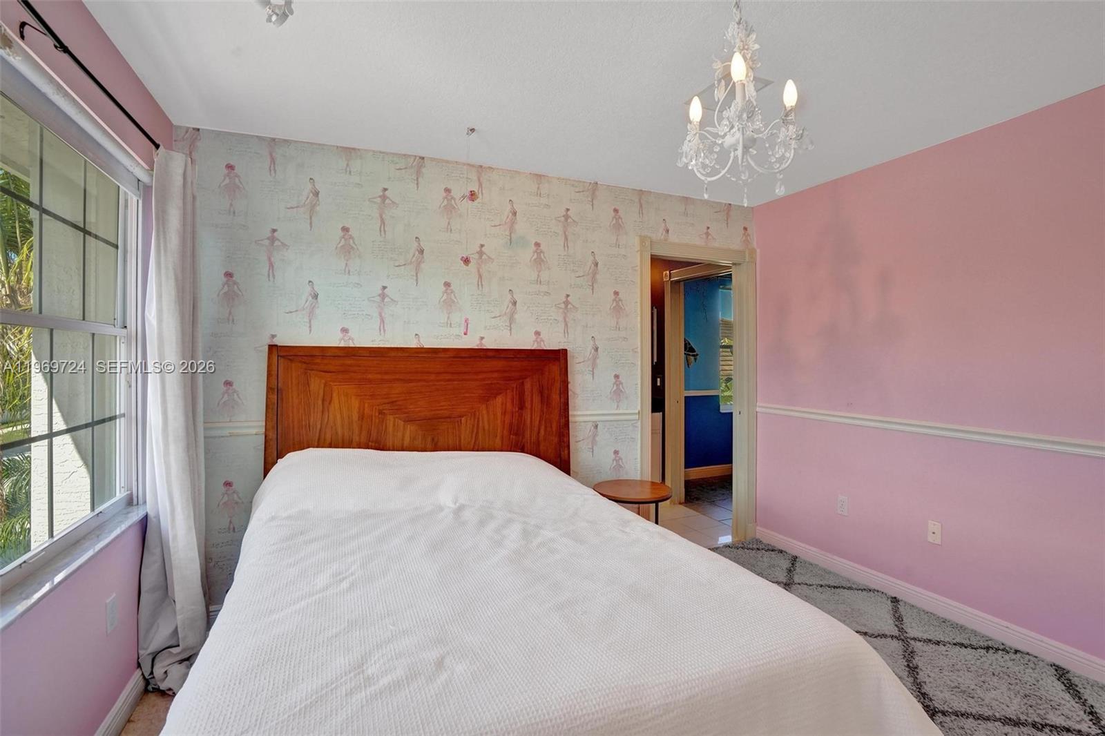 17431 Southwest 35th Street Miramar, FL 33029 - Photo 26 of 61 a bedroom with a large bed and a chandelier next to a window