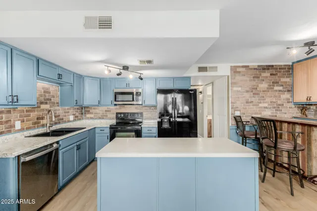 a kitchen with stainless steel appliances a sink stove refrigerator and cabinets