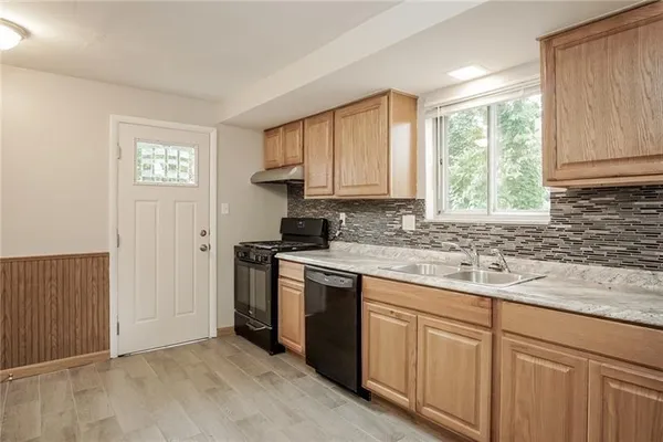 a kitchen with stainless steel appliances granite countertop white cabinets a sink and a window