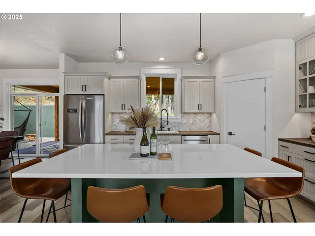 a kitchen with stainless steel appliances a dining table chairs and refrigerator
