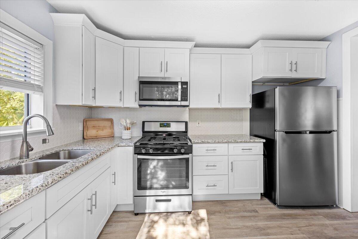 115 Milton Road Pensacola, FL 32507 - Photo 6 of 18 a kitchen with stainless steel appliances granite countertop a refrigerator stove a sink and white cabinets with wooden floor