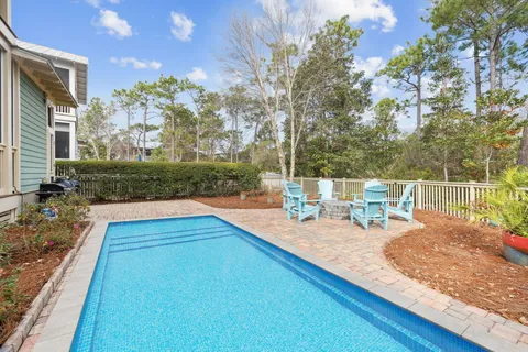 a view of a swimming pool with a patio and wooden fence