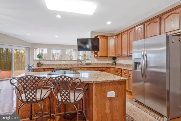 a kitchen with stainless steel appliances granite countertop a refrigerator a sink a stove and white cabinets with wooden floor