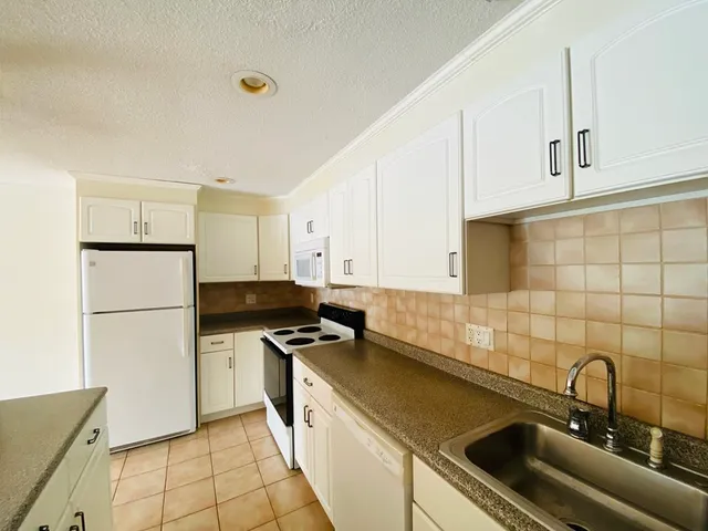 a kitchen with a sink a refrigerator and cabinets