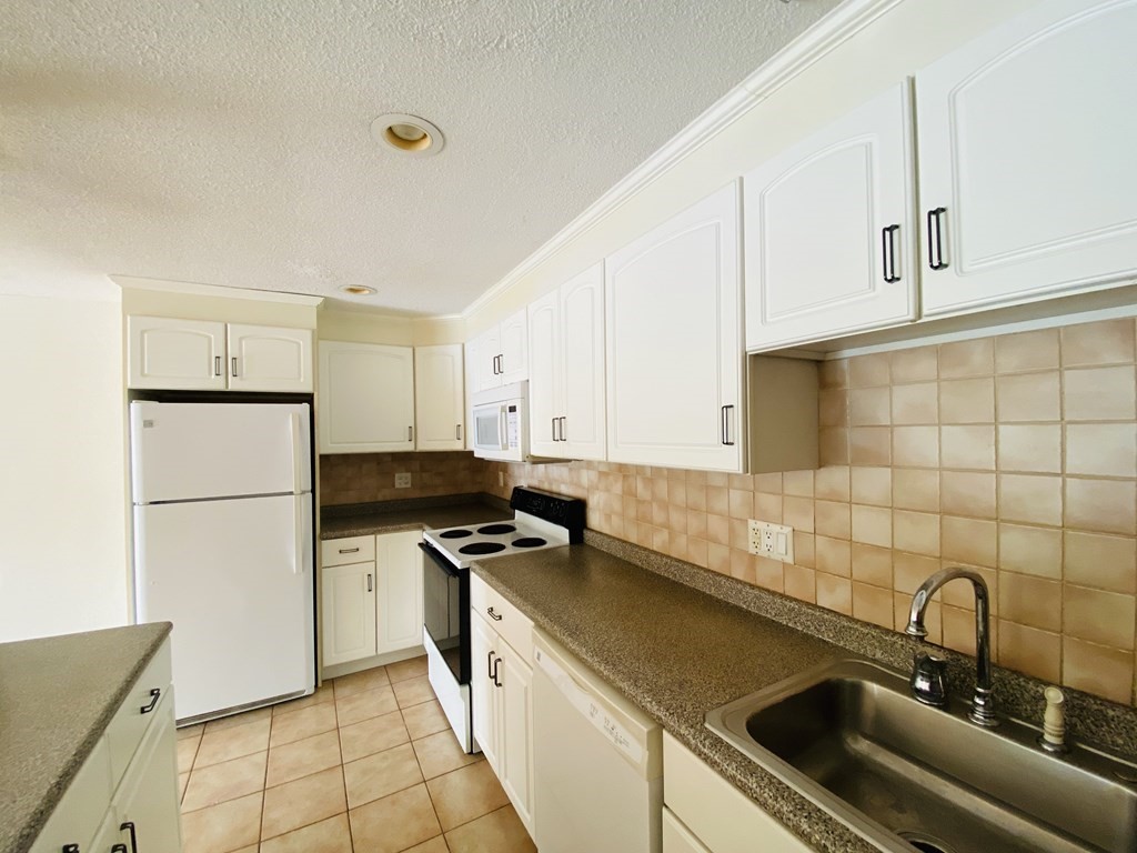 50 Green Street, Unit 209 Brookline, MA 02446 - Photo 4 of 16 a kitchen with a sink a refrigerator and cabinets