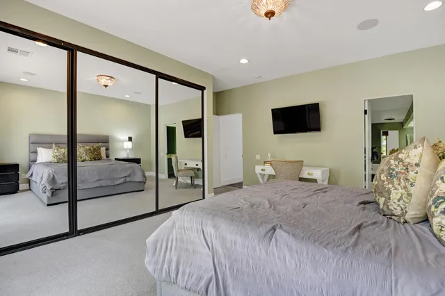 a bedroom with a large bed and a flat tv screen on dresser