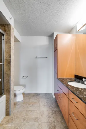 a bathroom with a granite countertop sink a toilet and shower