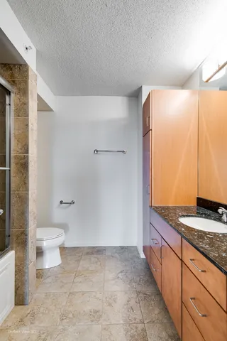 a bathroom with a granite countertop sink a toilet and shower